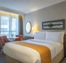 Cosy hotel room with double bed, seating area, and scenic window view.