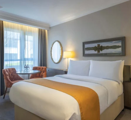 Cosy hotel room with double bed, seating area, and scenic window view.
