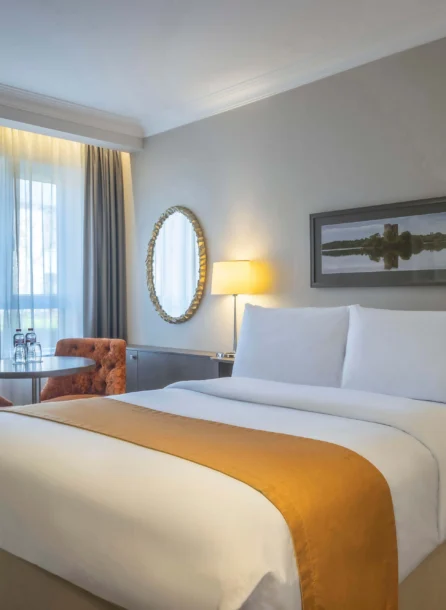 Cosy hotel room with double bed, seating area, and scenic window view.