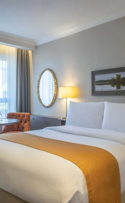 Cosy hotel room with double bed, seating area, and scenic window view.