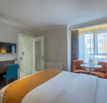 Cosy hotel room with a large bed, seating area, and natural light.