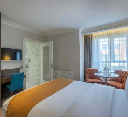 Cosy hotel room with a large bed, seating area, and natural light.