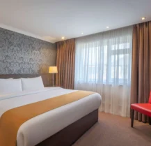 Modern hotel room with double bed and soft lighting.