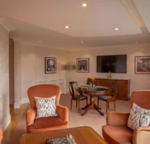 Elegant hotel suite with armchairs, dining table, and wall art.