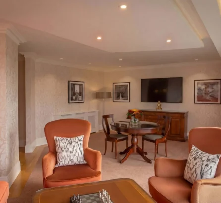 Elegant hotel suite with armchairs, dining table, and wall art.