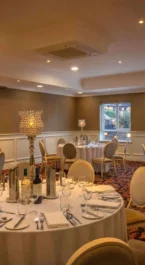 Elegant dining room at Hotel Kilmore set for a family gathering, with round tables and ambient lighting.
