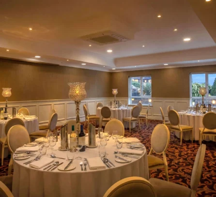 Elegant dining room at Hotel Kilmore set for a family gathering, with round tables and ambient lighting.