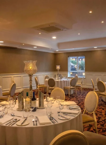 Elegant dining room at Hotel Kilmore set for a family gathering, with round tables and ambient lighting.