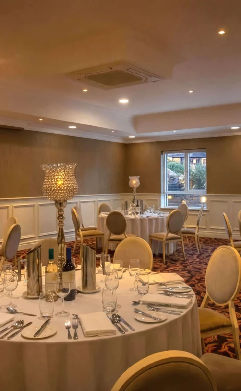 Elegant dining room at Hotel Kilmore set for a family gathering, with round tables and ambient lighting.