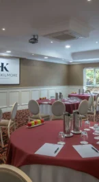 Elegant hotel conference room with round tables, set for a meeting.