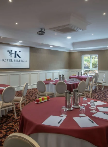 Elegant hotel conference room with round tables, set for a meeting.