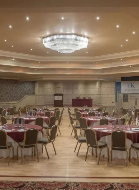 Elegant banquet hall in Hotel Kilmore set for an event, with round tables and red decor.
