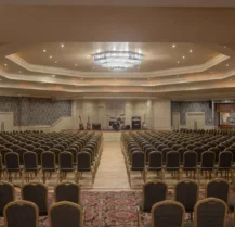 Spacious hotel function room with elegant decor and rows of seating, ready for guests.