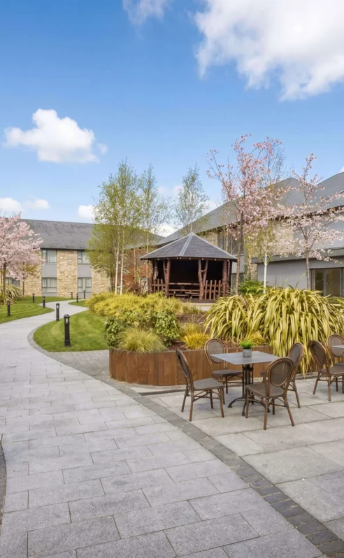 A charming hotel courtyard with cherry blossoms and outdoor seating on a sunny day.