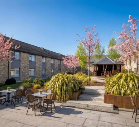 A peaceful courtyard at Hotel Kilmore with tables, chairs, and blossoming trees.