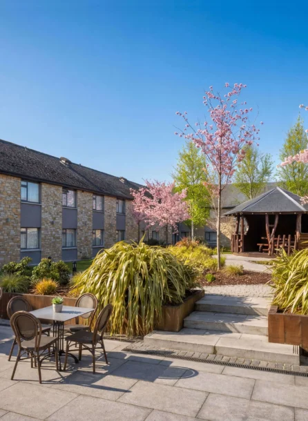 A peaceful courtyard at Hotel Kilmore with tables, chairs, and blossoming trees.