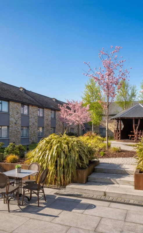 A peaceful courtyard at Hotel Kilmore with tables, chairs, and blossoming trees.