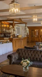 Cosy hotel lounge with a welcoming bar, floral decorations, and plush seating.