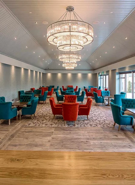 Spacious, elegant hotel lounge with vibrant teal and red seating, featuring families relaxing.