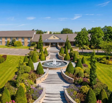 Aerial view of Hotel Kilmore entrance with lush gardens and a central fountain under a clear sky.