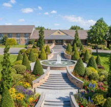 Grand entrance of Hotel Kilmore with lush gardens and a central fountain.