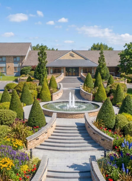 Grand entrance of Hotel Kilmore with lush gardens and a central fountain.