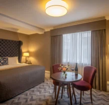Welcoming hotel room with a cosy bed and a table set for two.