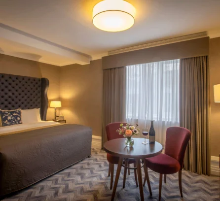 Welcoming hotel room with a cosy bed and a table set for two.