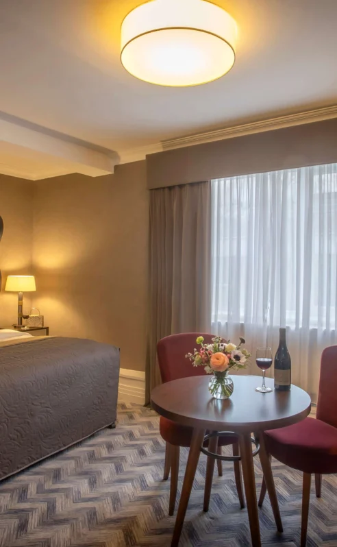 Welcoming hotel room with a cosy bed and a table set for two.