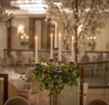 Elegant hotel dining room with candlelit tables and floral centrepieces, ready for guests.