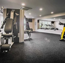 Modern hotel gym with exercise bikes and weight machines; mirrors create a spacious feel.