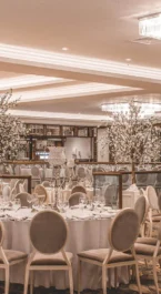 Elegant hotel banquet hall setup for a family event with round tables and chandeliers.