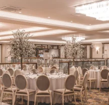 Elegant hotel banquet hall setup for a family event with round tables and chandeliers.