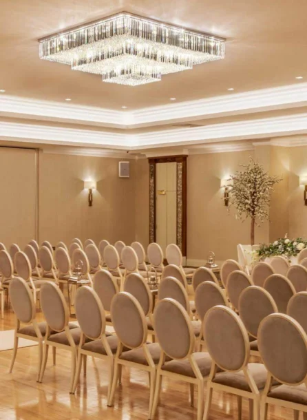 Elegant hotel event room set up for a family wedding ceremony with flower arrangements.