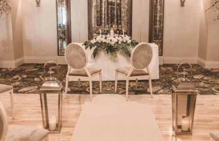 Elegant hotel wedding setup with floral arrangements and elegant chairs.