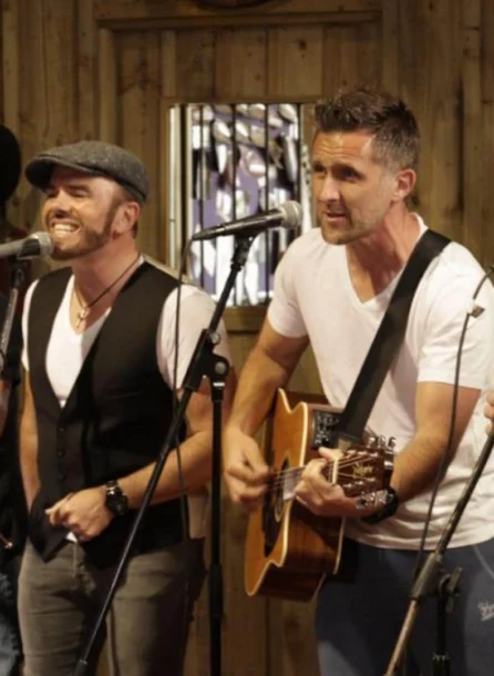 A lively band performing music in a cosy hotel setting, engaging a cheerful audience.