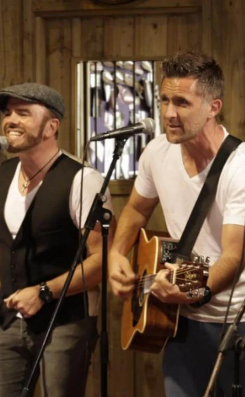 A lively band performing music in a cosy hotel setting, engaging a cheerful audience.