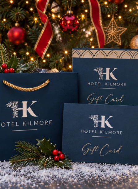 Festive Hotel Kilmore gift cards and bag near a Christmas tree with ornaments.