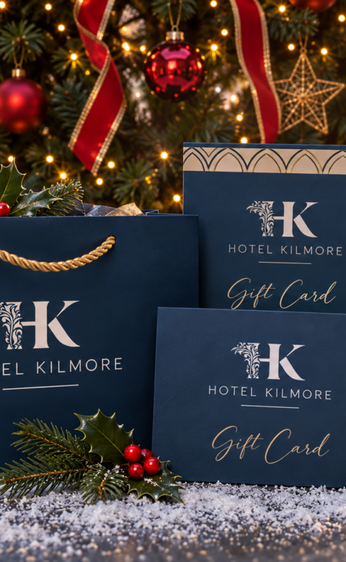 Festive Hotel Kilmore gift cards and bag near a Christmas tree with ornaments.